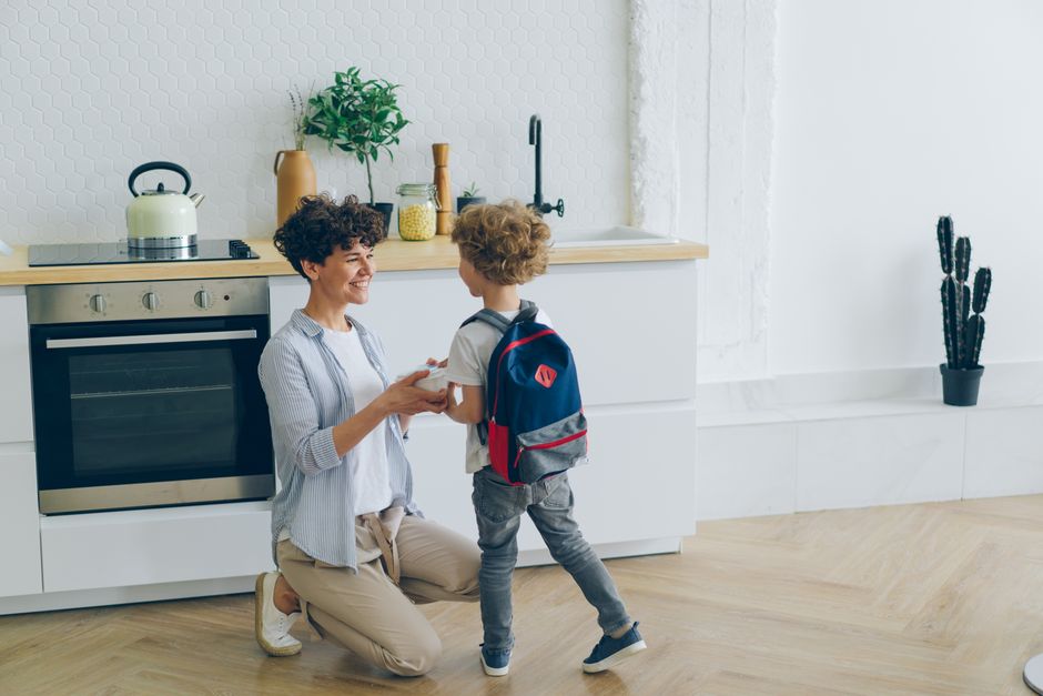 Mother shares a loving moment with her son before school in a modern kitchen.