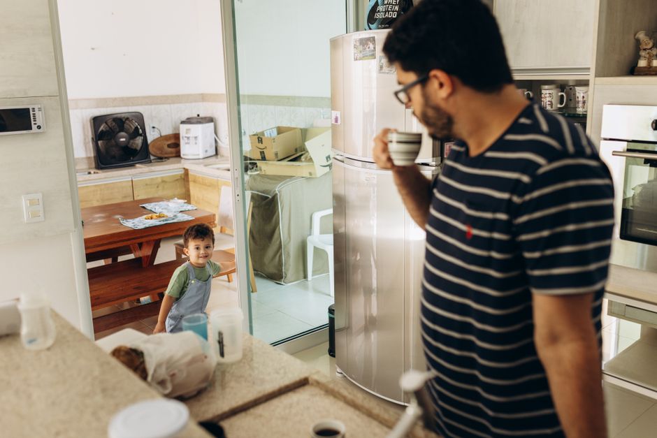 Father and young son sharing a moment in the kitchen with coffee and smiles.