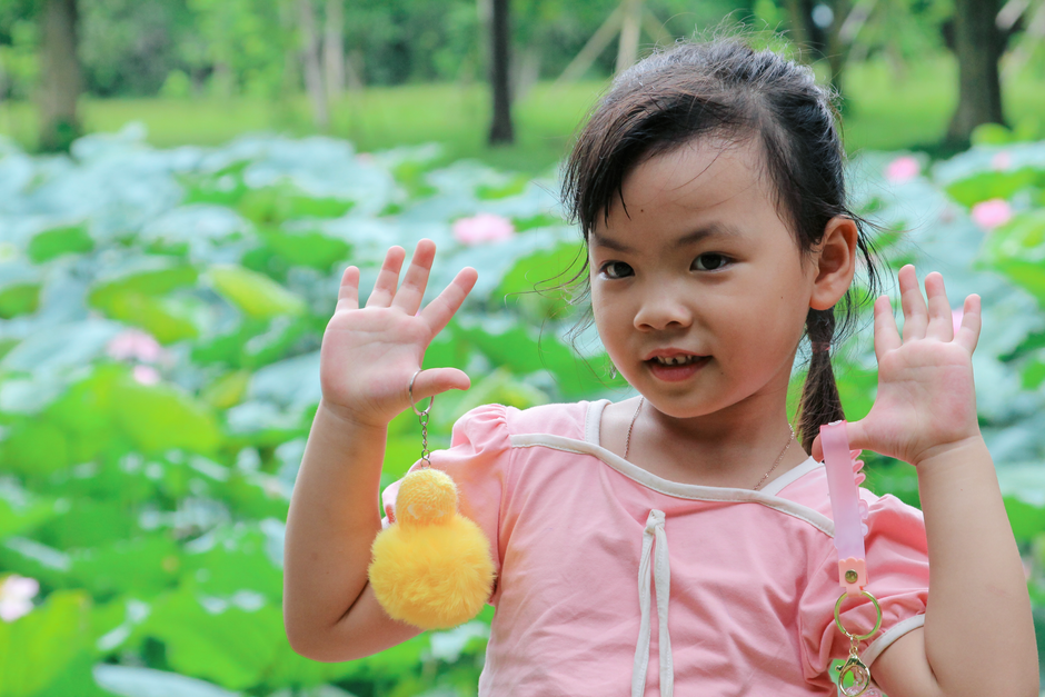 Smiling young girl with a fluffy toy in a lush green park during summer.