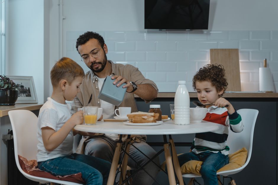 Father and sons enjoying breakfast together at a modern kitchen table.