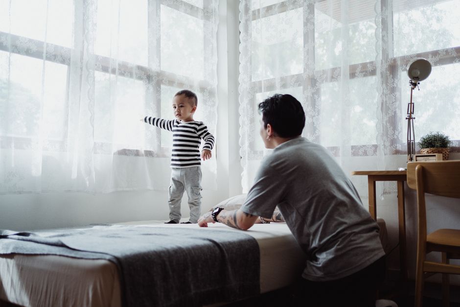 A father engages with his son in a bright and cozy bedroom setting, emphasizing family time.